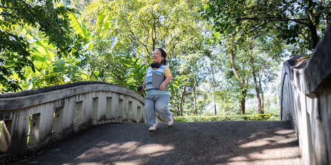 Joyful child with achondroplasia running on a bridge in a lush green park