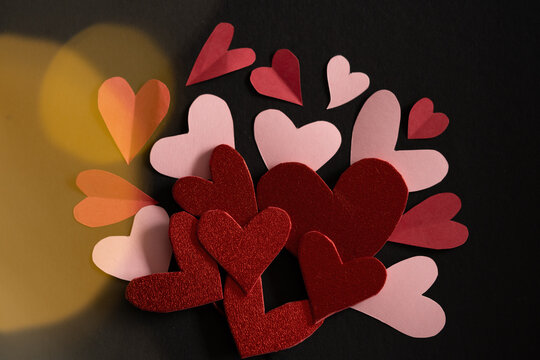 Composici&oacute;n de corazones de diferentes materiales con fondo negro y bokeh dorado