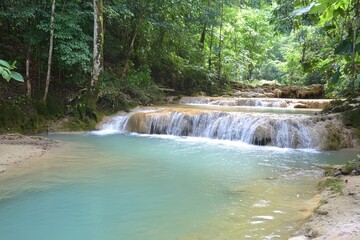 Serene Waterfall Cascading Over Rocky Terrain in a Lush Tropical Forest Surrounded by Verdant Foliage and Crystal Clear Aquamarine Pool