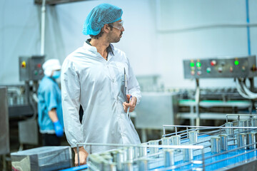 Inspector checking automated machinery in food production facility Focus on quality control safety and workflow efficiency. Worker overseeing food packaging machinery in a modern manufacturing plant.