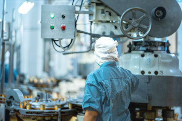 Inspector checking automated machinery in food production facility Focus on quality control safety and workflow efficiency. Worker overseeing food packaging machinery in a modern manufacturing plant.