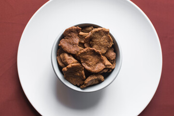 Overhead view of kuli-kuli on a white plate, top view of nigerian groundnut cakes on a plate, fresh homemade nigerian kulikuli on a ceramic plate