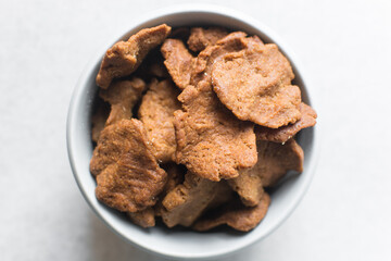 Overhead view of kuli-kuli in a white bowl, top view of nigerian groundnut cakes in a bowl, fresh homemade nigerian kulikuli in a ceramic bowl	