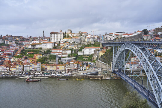 Porto, Portugal - March 10, 2024: High angle view of cruise ships moored on Douro River under Dom Luis I Bridge with houses on the hill of old town