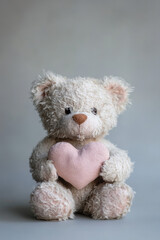 Obraz premium Adorable fluffy teddy bear holding a soft pink heart, symbolizing love and comfort in a serene setting.