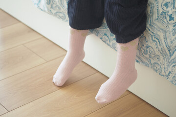 Cute and Cozy Pink Socks Playfully Hanging Off the Side of the Bedside