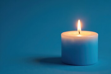 Warm softly lit blue candle on blue background, tranquility, cozy atmosphere