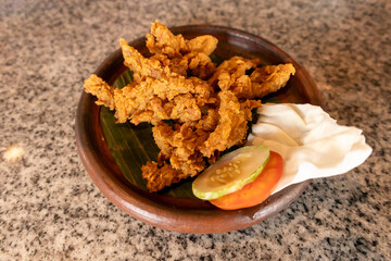 Fried flour mushrooms with vegetables served on a clay plate with a banana leaf base