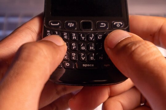 Jakarta, Indonesia - January 08, 2025: Hands typing on Blackberry cellphone keypad