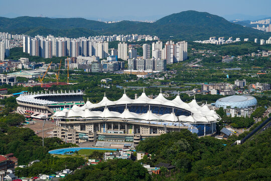 Munhak-dong, Nam-gu, Incheon, South Korea - May 31, 2024: High angle and summer view of Incheon Munhak Stadium in the forest against apartments seen from Munhaksan Mt.