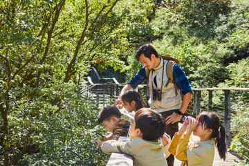 Happy teacher and kids hiking in the mountains