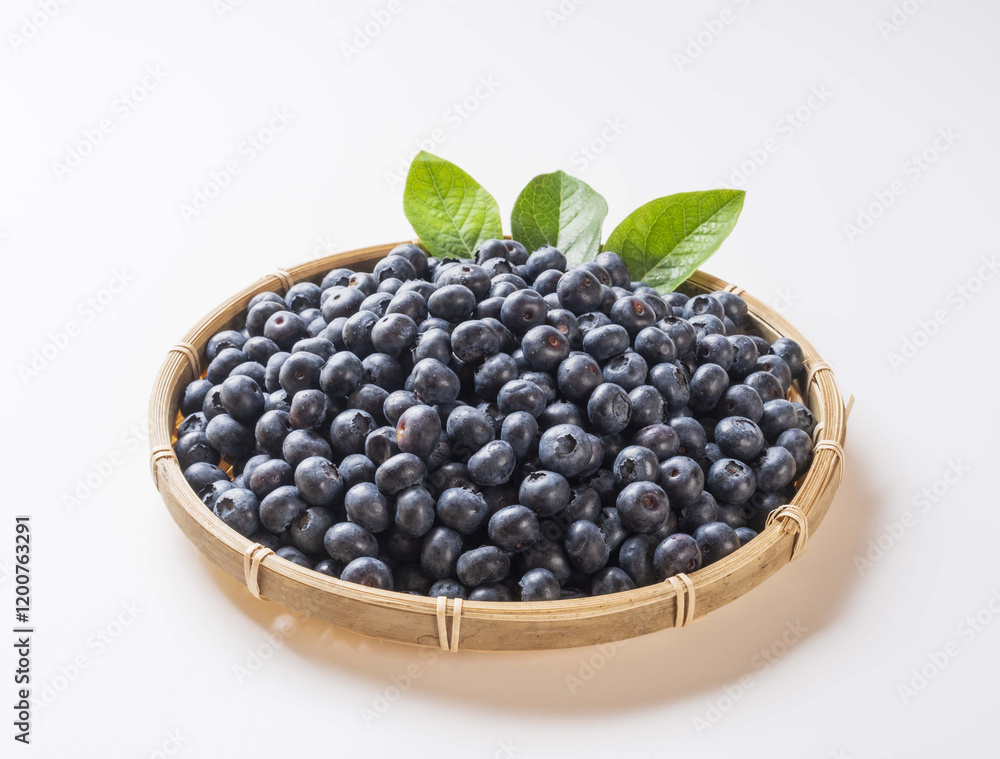 Wall mural Close up of raw blueberries with purple fruits and green leaf on bamboo basket and white floor, South Korea