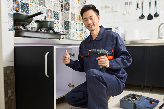 Handyman repairing the kitchen cabinet - Powered by Adobe