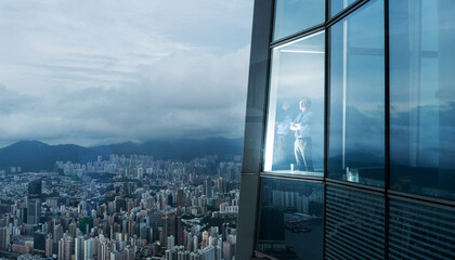 Successful businessman in suit standing in office looking through window at big city buildings