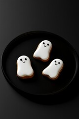 Cute ghost cookies on a black plate, a cute and creepy Halloween concept.