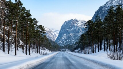 Fototapeta premium Snow-covered road winding through a mountainous landscape.