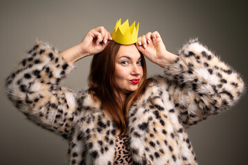 A stylish woman with a funny delusion of grandeur in a leopard print coat and vibrant yellow crown...