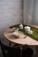 A stylish dining table with a charming vase, elegant dishes, bowl with oatmeal bowl. Cozy breakfast.