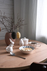A stylish dining table with a charming vase, elegant dishes, bowl with oatmeal bowl, egg. Easter decoration.