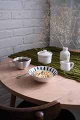 A stylish dining table with a charming vase, elegant dishes, bowl with oatmeal bowl. Cozy breakfast.
