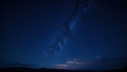 Fototapeta premium A mesmerizing midnight canvas reveals a deep indigo sky speckled with twinkling stars. The Milky Way arches majestically at its heart, weaving an ethereal path across the heavens