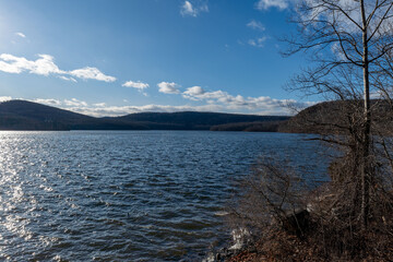 Serene lake view with distant mountains under a partly cloudy sky.  Peaceful landscape photo perfect for nature-themed projects.