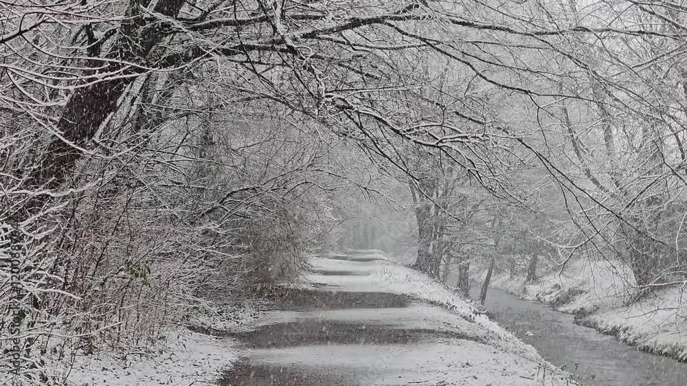 Poster snowy winter path along a stream in the sauerland in slow motion