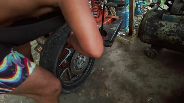 In a bustling Filipino vulcanizing shop, street mechanics replace motorcycle tires. This hands-on scene showcases the skills of local workers and the vibrant street culture in the Philippines