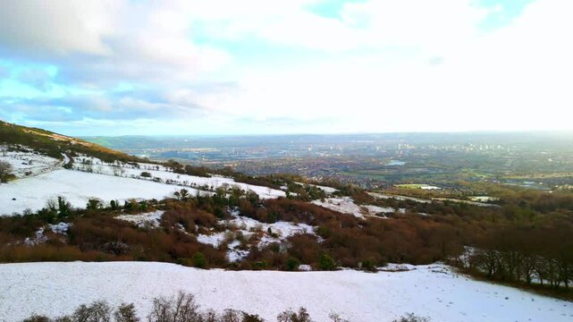 Aerial shot of Cavehill in Belfast, Northern Ireland on a snowy and calm winter day. The camera advances over the snowy mountain, revealing Belfast City. Shot in 4K, 60fps and in Rec709 color.