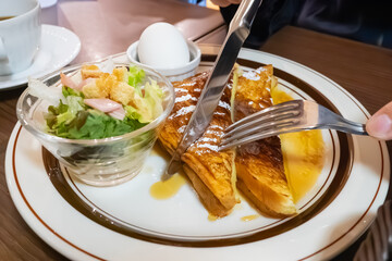 カフェで食べる朝食。甘いシロップがかかったフレンチトーストを食べてる人。