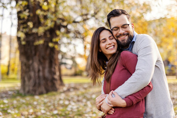 Young sweet couple hugging with eyes closed and spending time together in city park.