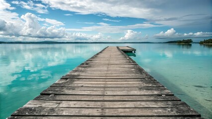 Obraz premium A weathered wooden dock juts out into the calm turquoise waters, natural light, wooden dock, beachy atmosphere, driftwood