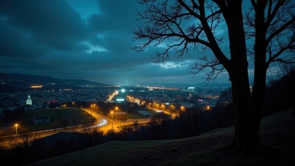 Fototapeta premium Nighttime cityscape under starry skies, framed by rolling hills and a lone tree silhouetted against the city lights below. Clouds scatter across the dark blue heavens, adding depth to the tranquil sce