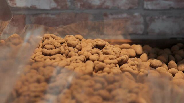 Chocolate covered pecans nestled in cellophane bags, arranged against weathered brick backdrop, promising rich, decadent snacking experience