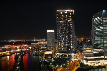 日本の横浜。高層ビルの明かりが運河に反射する夜景。