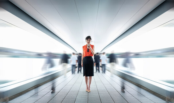Woman using phone and walking on footbridge