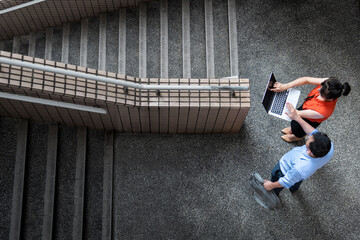 Young woman and man are discussing work on staircase