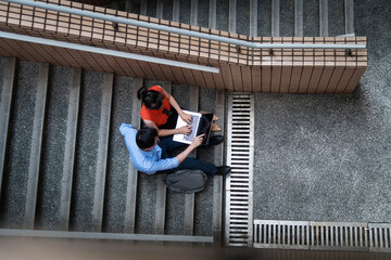 Young woman and man are discussing work on staircase