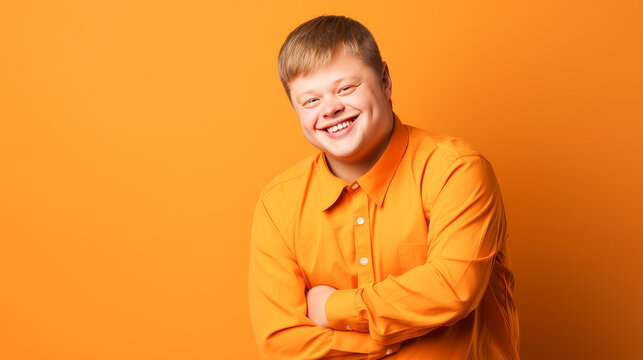 Portrait of smiling laughing man with Down syndrome orange background.