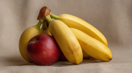 Ripe yellow bananas and a red apple on a beige background.