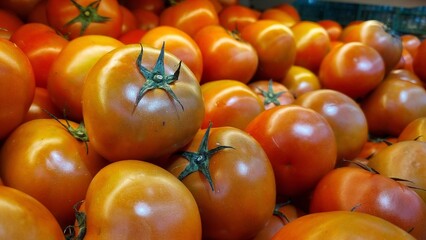 Close-up view of ripe juicy red tomatoes. Red tomatoes on the market stall at supermarket. Vibrant organic red tomatoes texture background ideal for fresh produce and healthy eating concepts.
