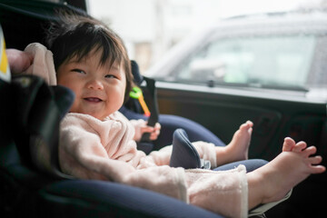 6-month-old Japanese baby girl is in baby seat in back seat of car.