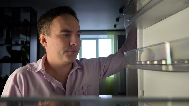 POV point of view from inside refrigerator Caucasian hungry man adult sad upset disappointed male. guy looking for good open empty fridge no food without products. crisis delivery supermarket