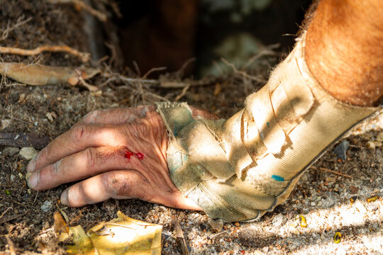mans hand on ground fingers blood spot