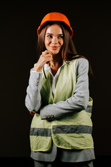 Woman engineer in safety gear poses confidently against a black background showcasing her professionalism and expertise