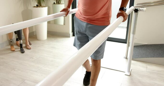Man in prosthetic leg walking using parallel bars for rehabilitation therapy