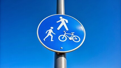 Close-up Bottom View: Blue & White Pedestrian & Bicycle Crossing Signs Against a Clear Blue Sky