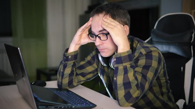 man working holding sore head pain from desk working and sitting all day using laptop computer suffering headache sick worker overworking concept. fatigue and burnout at work is a concept.