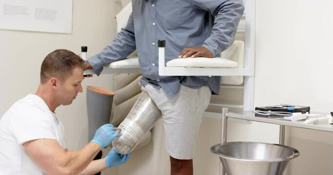 Technician fitting prosthetic leg for patient in medical lab setting