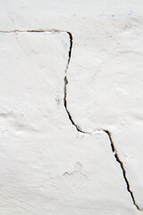 A close-up crack in a white wall. An old whitewashed wall.